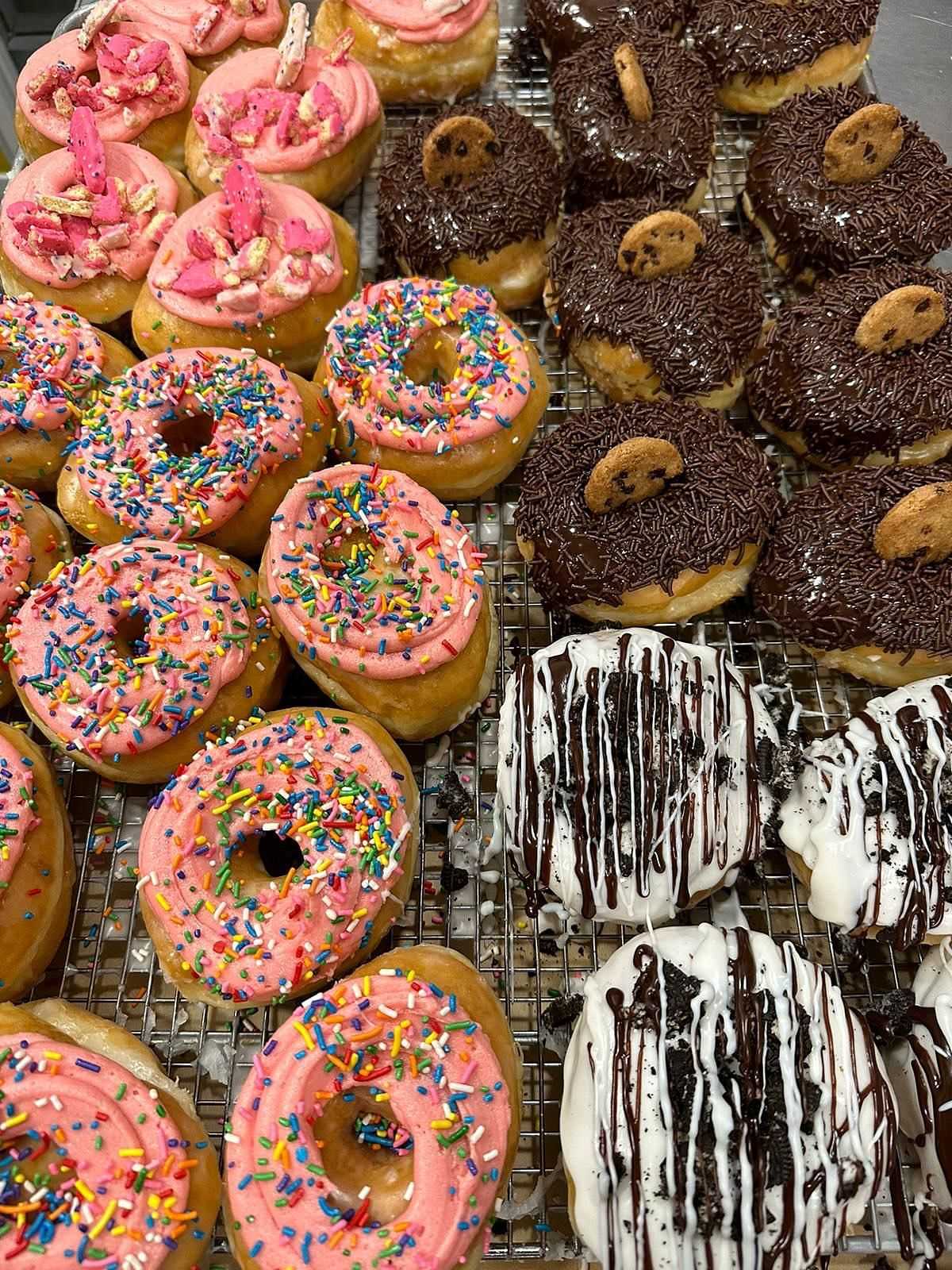 Assorted frosted donuts with sprinkles and toppings on a tray.