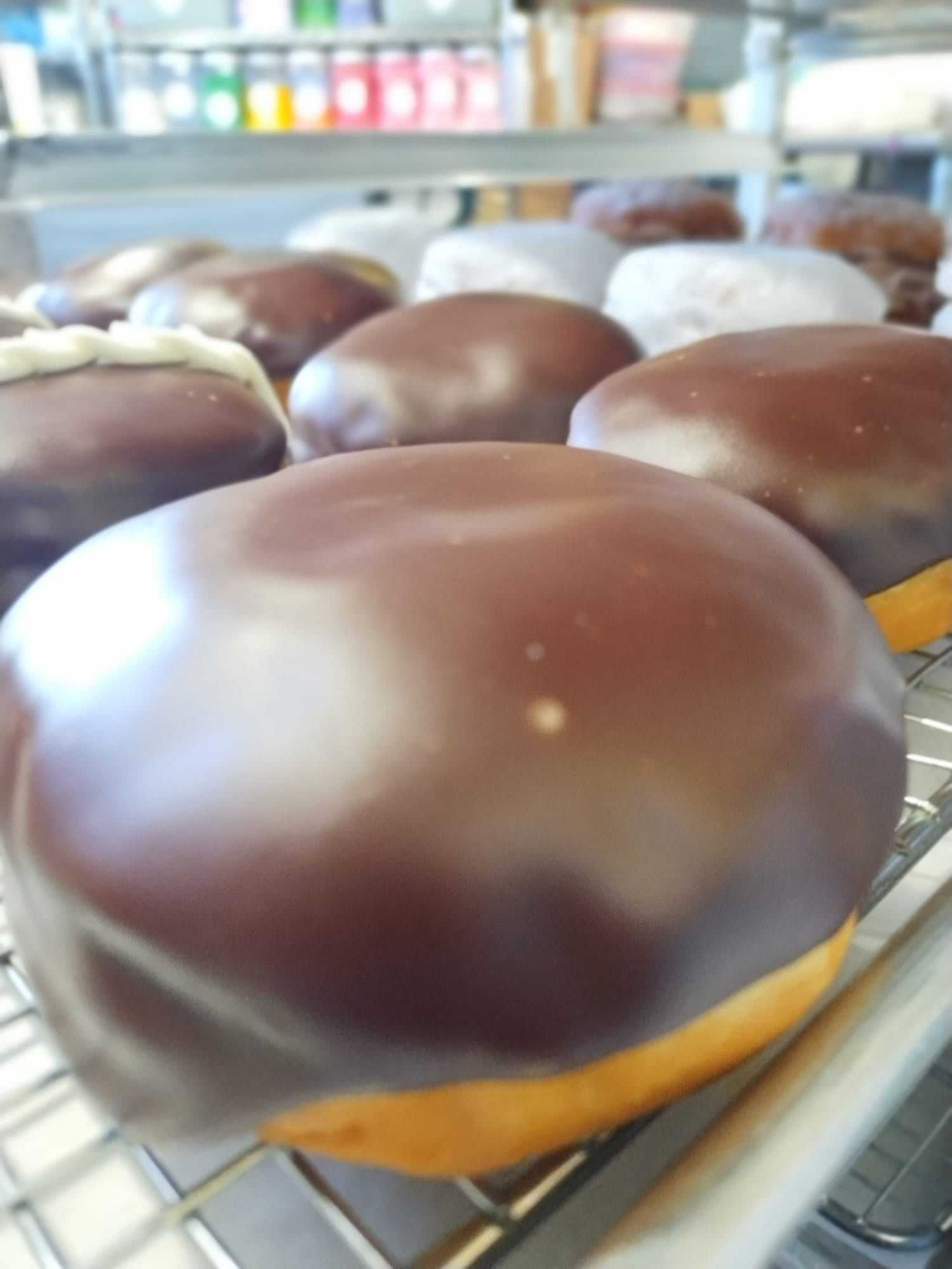 Close-up of chocolate glazed donuts on a bakery rack.