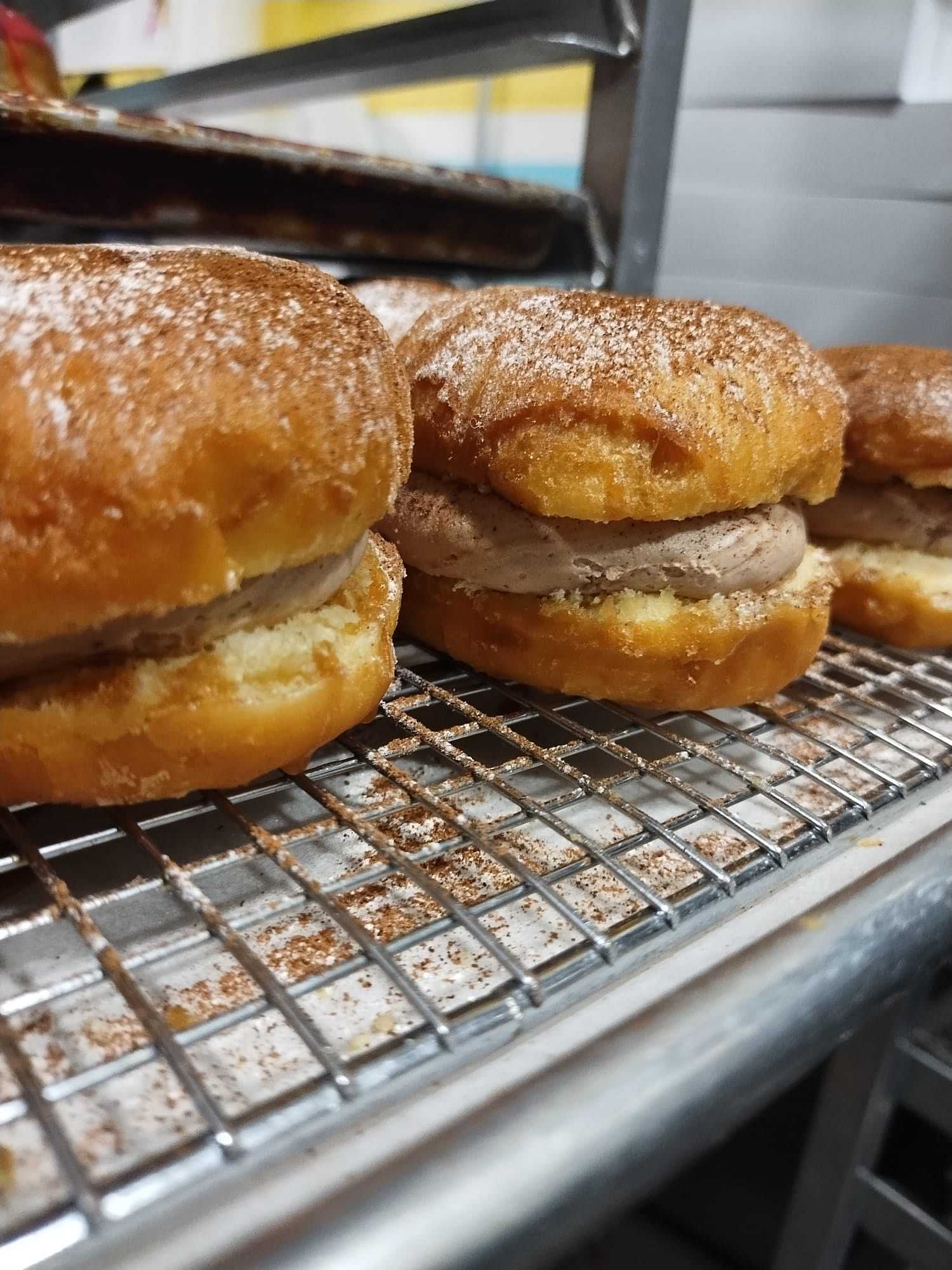 Freshly baked donuts with sugar topping on a cooling rack.